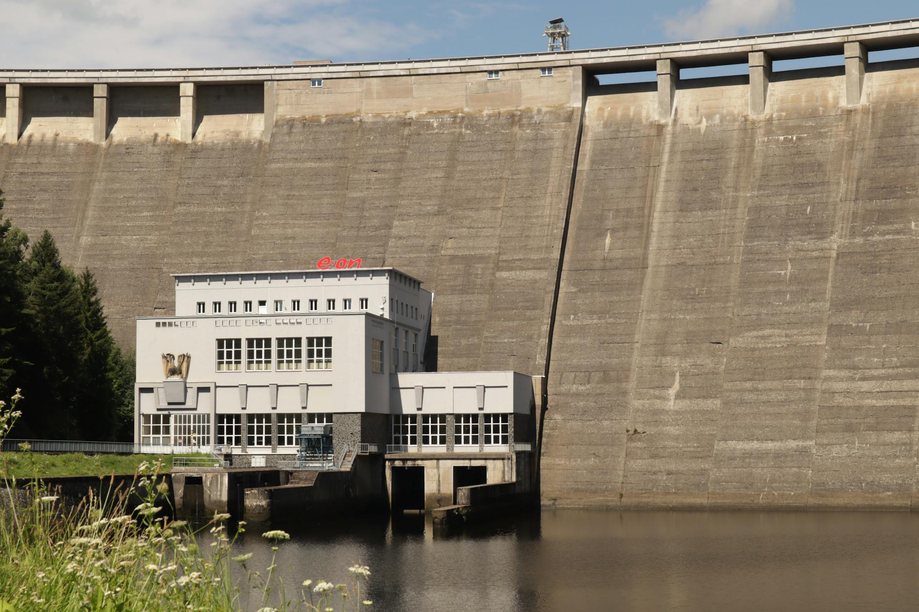 A large dam in Czechia with an adjacent building by a calm water body.